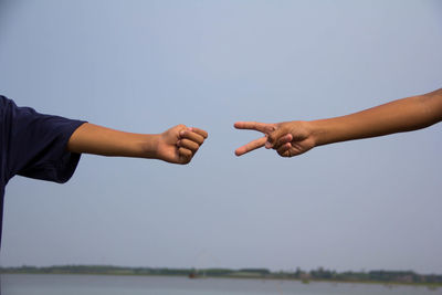 Low angle view of people hands against clear sky