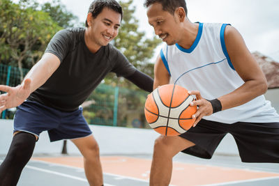 Friends playing basketball at court