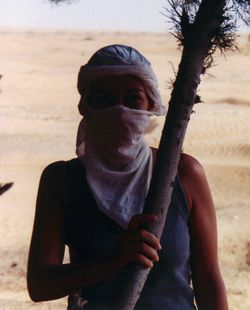Portrait of man holding sunglasses on beach