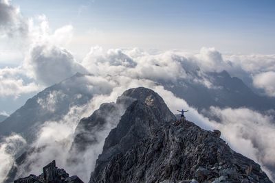 Person standing on mountain against cloudy sky
