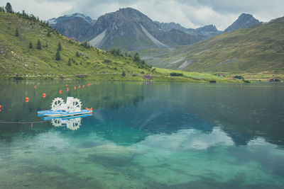 Tignes lake with pedal boat at the foot of the haute tarentaise mountains under a stormy sky