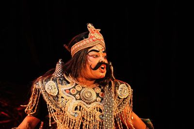 Portrait of young woman standing against black background