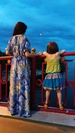 Rear view of two women standing against the wall