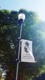 Low angle view of text on street light against sky