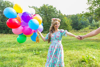 Woman holding balloons on field