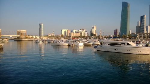 Boats moored in sea by city against clear sky