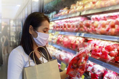 Woman holding apples while standing in supermarket