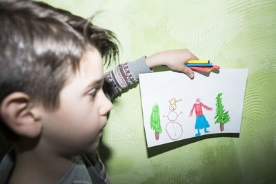 Portrait of boy holding painting on wall