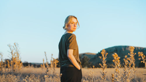 Side view of woman standing on field against clear sky