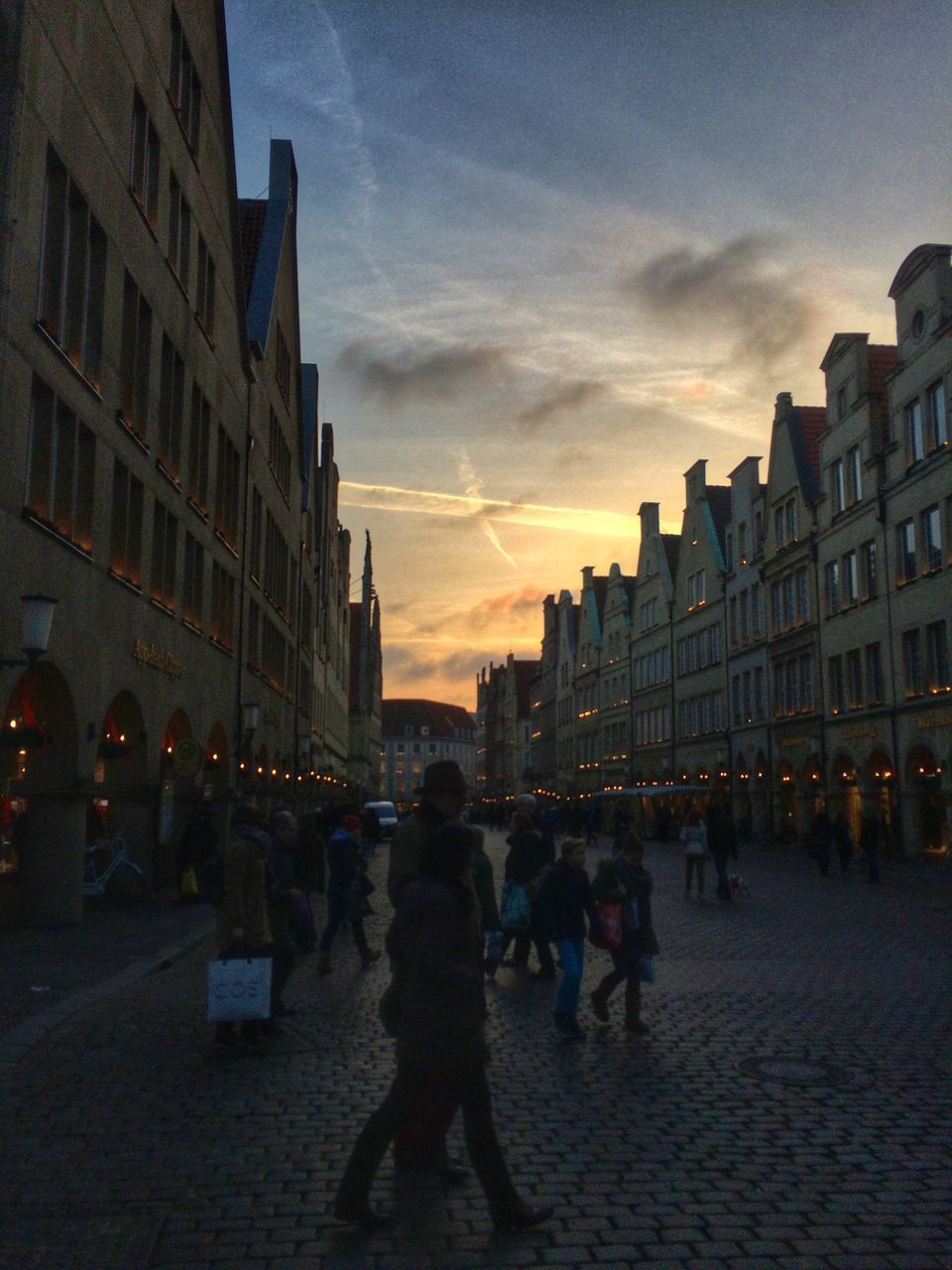 architecture, building exterior, built structure, large group of people, city, sunset, lifestyles, men, person, city life, sky, walking, street, leisure activity, silhouette, building, dusk, mixed age range, illuminated