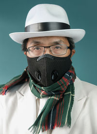 Portrait of man wearing mask and hat against colored background