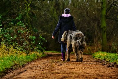 Woman with dog walking on dirt road