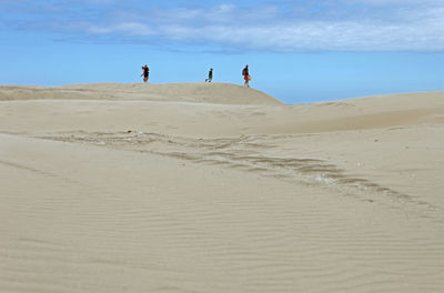 People at desert against sky