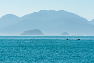 Scenic view of sea and mountains against clear sky