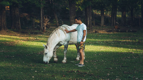 Full length of young woman with horse on field