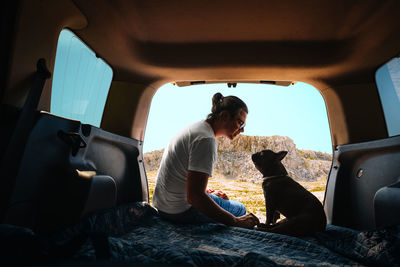 Man and french bulldog sitting and bonding in car trunk