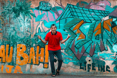 Full length portrait of man standing against graffiti