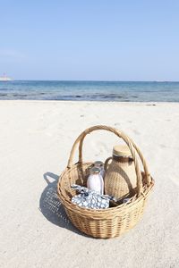 Wicker basket on beach against sky