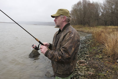 A fisherman, a man catches fish with a fishing rod, from the bank of the river. high quality photo