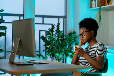 African american woman sits exploring plan of business project reading from working computer