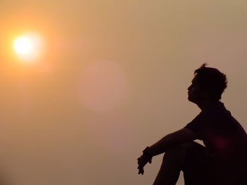 Silhouette man sitting against sky during sunset