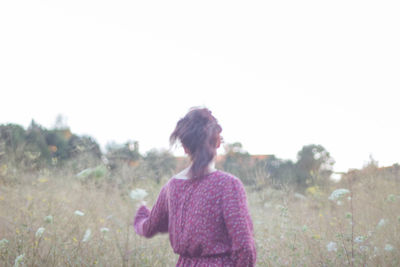 Rear view of woman standing on field against clear sky