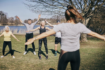 Rear view of female trainer teaching senior people on field at park