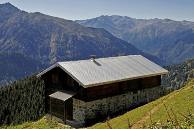 House amidst trees and mountains against sky