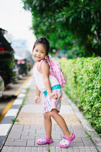 Portrait of cute girl with backpack posing on footpath