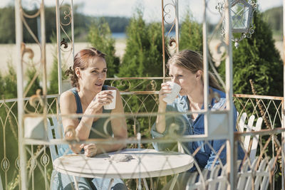 Female friends drinking coffee in back yard