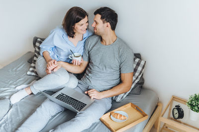 High angle view of couple romancing on bed at home