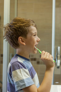 Close-up of boy brushing teeth at bathroom