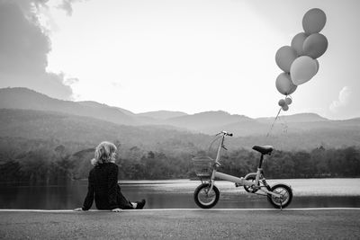 Rear view of woman with bicycle at lakeshore