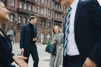 Smiling entrepreneur by male colleague standing on street in city