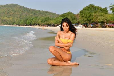 Sensuous young woman sitting at beach