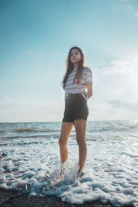 Full length of young woman on sea shore against sky