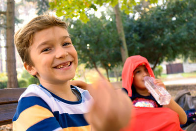 Portrait of smiling boy sitting with sister at park