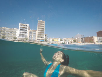 Man swimming in pool by sea against blue sky