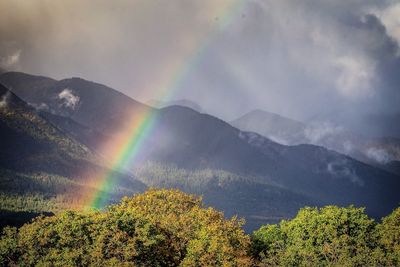 Scenic view of rainbow over mountain against sky