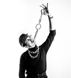 Young man holding chain against white background