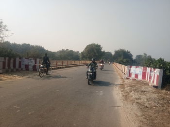 People riding bicycle on road against clear sky