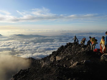 People on rock against sky