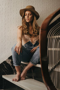 Full length of woman sitting against wall