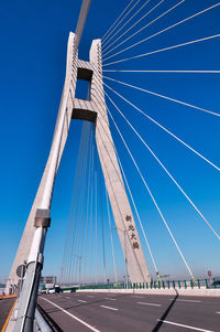 Low angle view of suspension bridge against blue sky