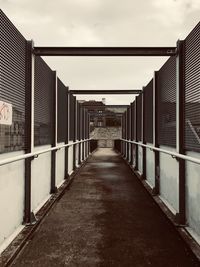 Empty footpath amidst buildings against sky in city