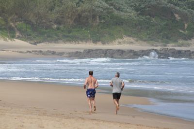 Rear view of friends walking on beach