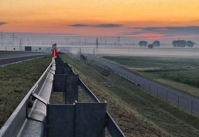 Scenic view of grassy field against sky at sunset