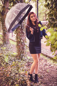 Portrait of young woman with umbrella standing at park