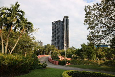 Park by modern buildings against sky