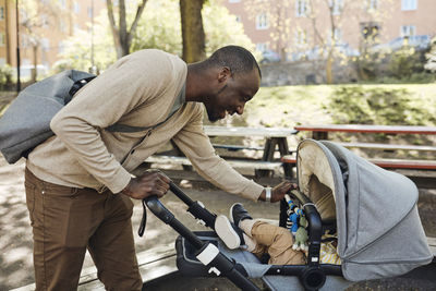 Smiling father looking at son in baby stroller
